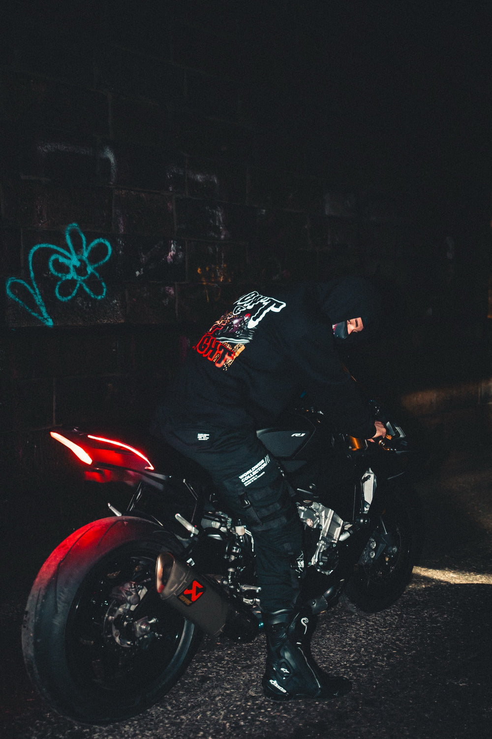 Hurt.Biker rider in hoodie on motorcycle at night, red taillight